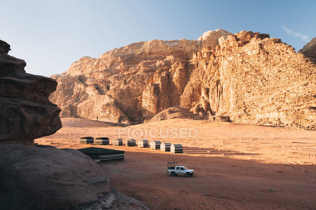 Veículo moderno estacionado perto de tendas de acampamento durante a viagem pelo deserto de Wadi Rum no dia ensolarado na Jordânia — Fotografia de Stock