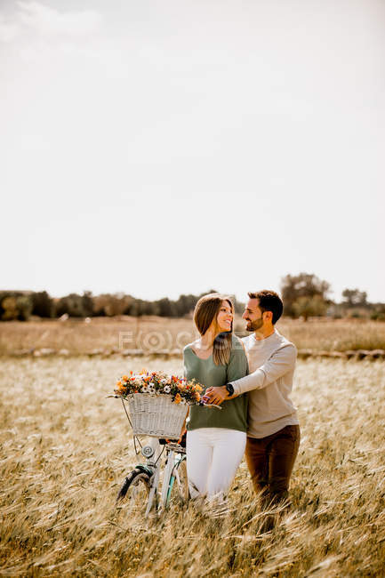 Sincere lovers posing by bicycle on rye field — Stock Photo