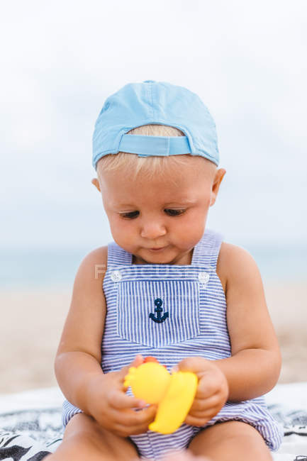 Портрет хлопчика, який грає з гумовими качками на пляжі — стокове фото