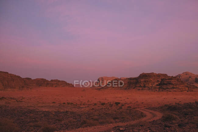 Ciel nuageux violet sur une crête montagneuse rugueuse et le désert de Wadi Rum dans la soirée en Jordanie — Photo de stock