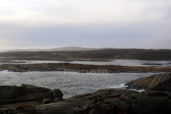 Rochers lisses sur la côte vide avec des vagues de mer sous un ciel nocturne sombre en Norvège — Photo de stock