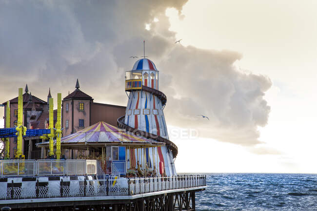 Colorful attractions of amusement park on pier near waving sea against cloudy sky in evening in Brighton, England — Stock Photo