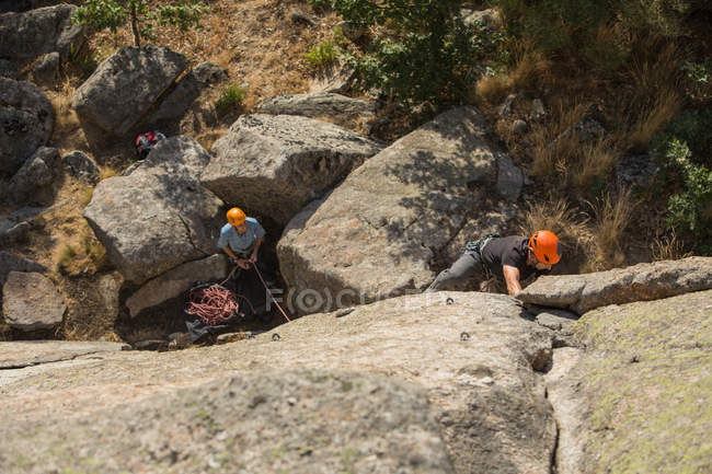 Adventurers climbing mountain, wearing safety harness against picturesque landscape — Stock Photo
