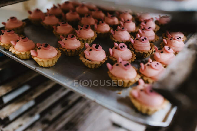 Bandeja de metal com saborosa massa em forma de porco colocada em rack na padaria profissional — Fotografia de Stock
