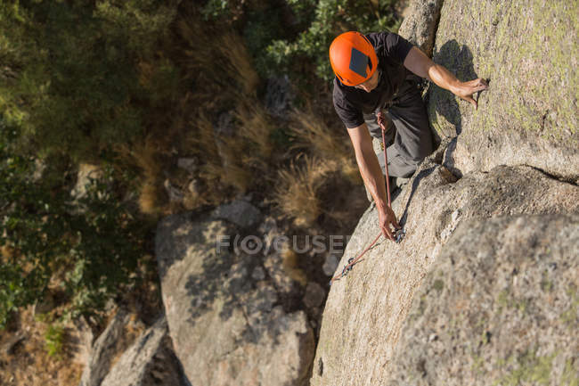 D'en haut l'homme escalade un rocher dans la nature avec des équipements d'escalade — Photo de stock