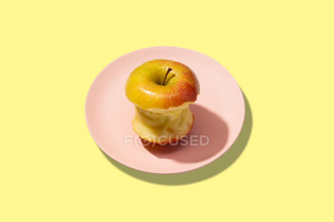 Mela fresca morsa in piatto su fondo giallo. Modello colorato vibrante — Foto stock