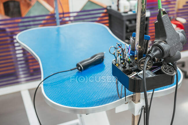 Rack with various tools for fur care placed near blue table in professional grooming salon — Stock Photo
