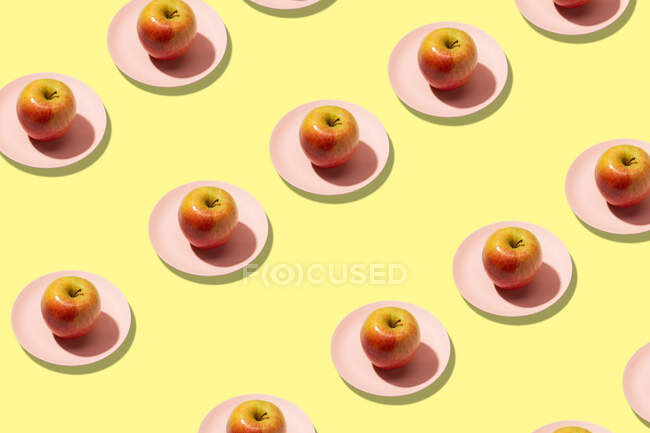 Maçãs frescas em placa sobre fundo amarelo. Padrão colorido vibrante — Fotografia de Stock