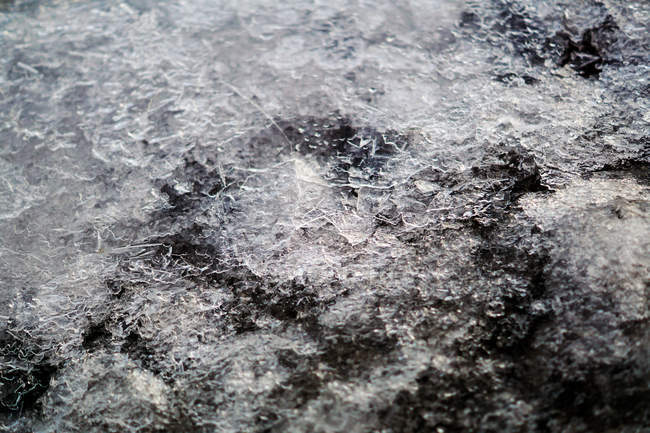 Sciogliere ghiaccio e neve sulla superficie rocciosa con ciottoli alla luce del giorno — Foto stock