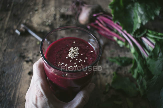 Person hand holding glass of organic delicious beetroot smoothie — Stock Photo