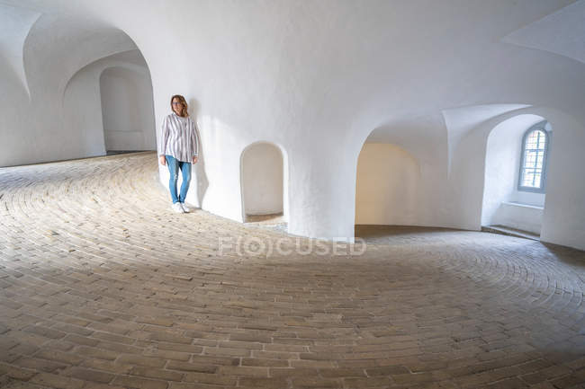 Lässige Frau lehnt an Wand in geräumiger Galerie mit Fenstern — Stockfoto