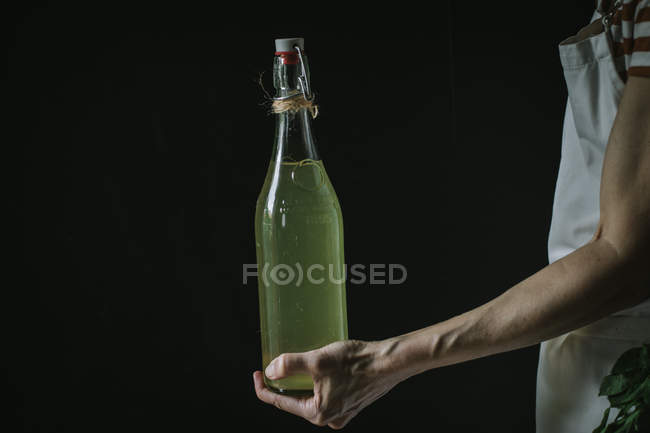 Main féminine avec bouteille de cidre de sureau — Photo de stock