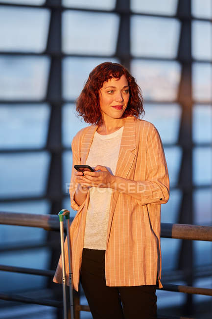Smiling young woman browsing on phone at station — Stock Photo
