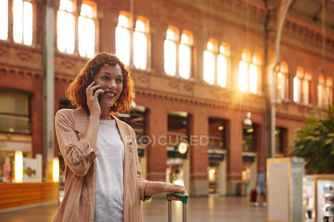 Jovem ruiva usando smartphone na estação — Fotografia de Stock