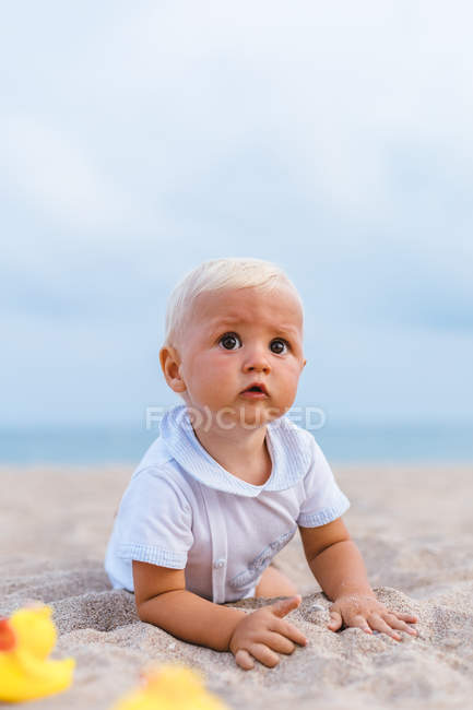 Portrait de bébé garçon jouant avec des canards en caoutchouc sur la plage — Photo de stock