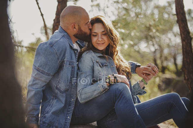 Una pareja sensual abrazando mientras se sienta en el valle de las montañas - foto de stock