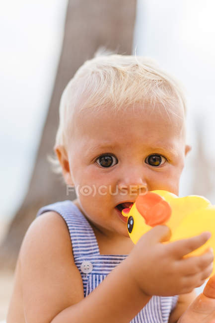 Портрет мальчика, играющего с резиновыми утками на пляже — стоковое фото