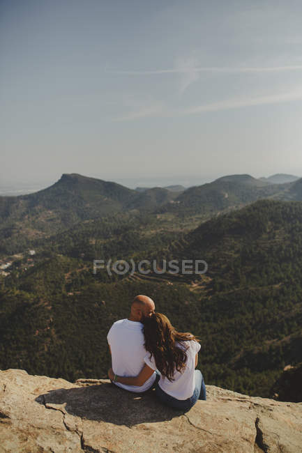 Happy couple sitting at mountain cliff — Stock Photo
