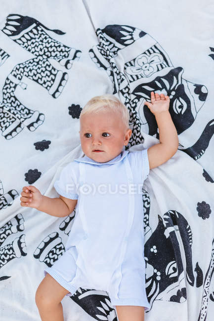Vista superior de un bebé rubio acostado en una manta - foto de stock