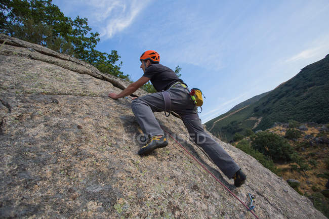 Mann besteigt mit Kletterausrüstung einen Felsen in der Natur — Stockfoto