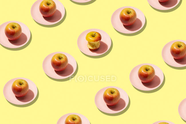 Fresh apples and bitten apple in plate on yellow background. Vibrant colorful pattern — Stock Photo