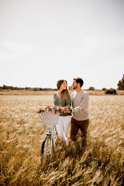Gli amanti sinceri in posa in bicicletta sul campo di segale — Foto stock