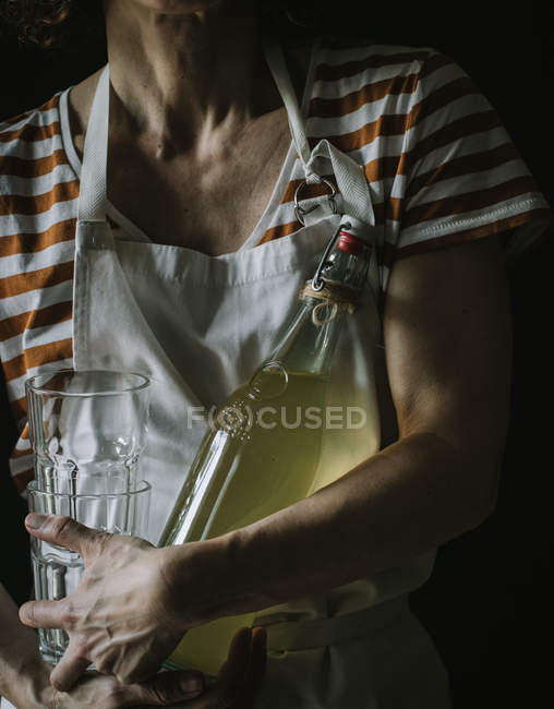 Cropped of woman holding bottle of elderflower lemonade and two glasses — Stock Photo