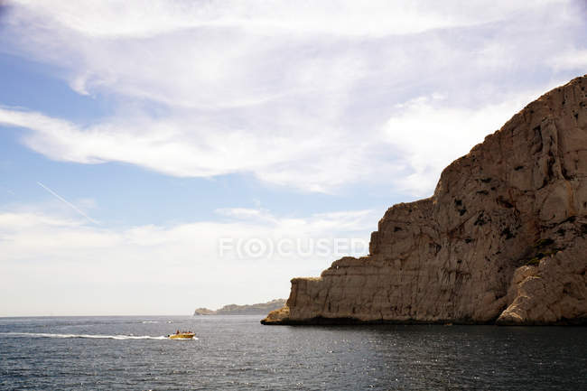 Limestone rocks and boat sailing in sea — Stock Photo