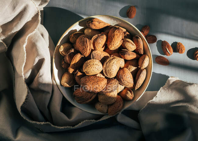 Bowl of almonds in shells on kitchen table — Stock Photo