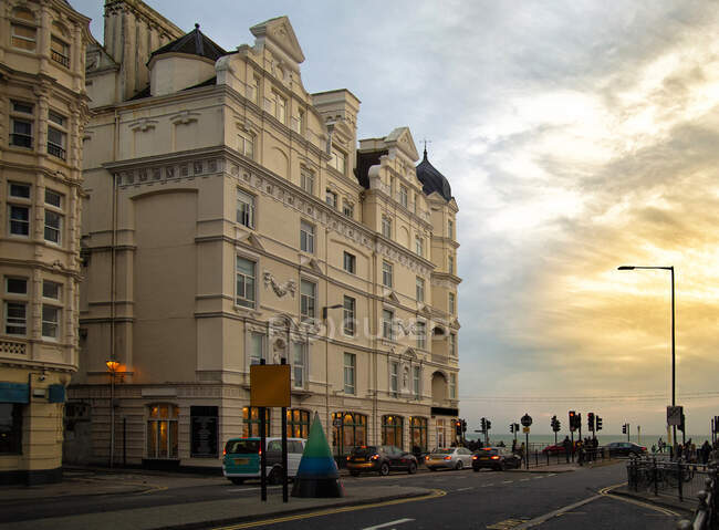 Edifício envelhecido ornamental e carros modernos contra céu nublado pôr do sol na rua de Brighton, na Inglaterra — Fotografia de Stock