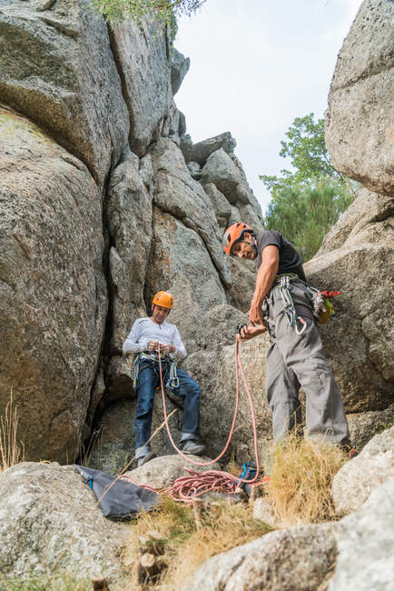 De baixo vista dos alpinistas preparando seu equipamento para começar a escalar — Fotografia de Stock
