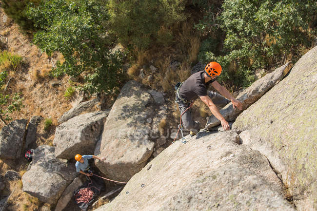 Человек карабкается по скале на природе с альпинистским снаряжением — стоковое фото