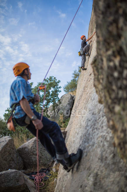 Aventureros escalando montañas, usando arnés de seguridad contra paisajes pintorescos - foto de stock