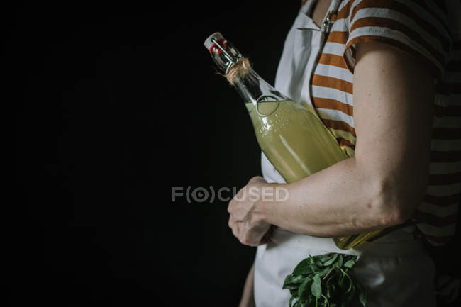 Vista lateral de la mujer con botella de bebida de flor de saúco - foto de stock