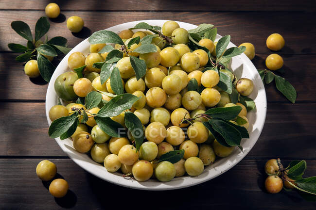 Fruta de mirabela de ameixa amarela fresca na tigela na mesa de madeira — Fotografia de Stock