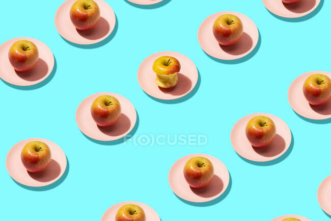 Fresh apples and bitten apple in plate on cyan background. Vibrant colorful pattern — Stock Photo