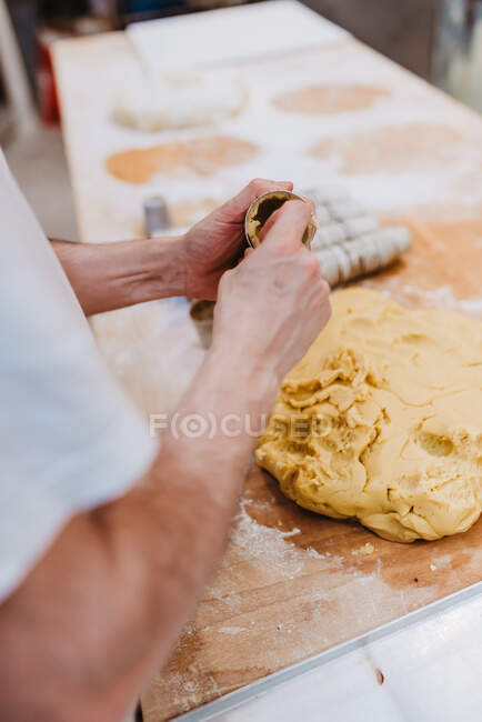 Coltivatore in t-shirt bianca che mette pasta fresca in tazze mentre fa la pasticceria in cucina di panetteria — Foto stock