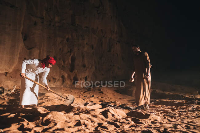 Hombres árabes cavando arena cerca del acantilado - foto de stock