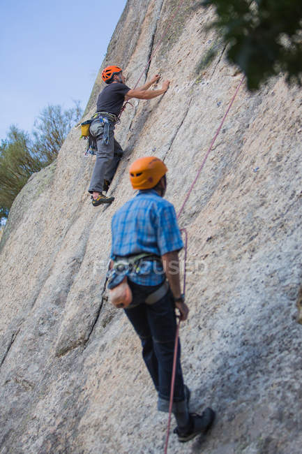Adventurers climbing mountain, wearing safety harness against picturesque landscape — Stock Photo