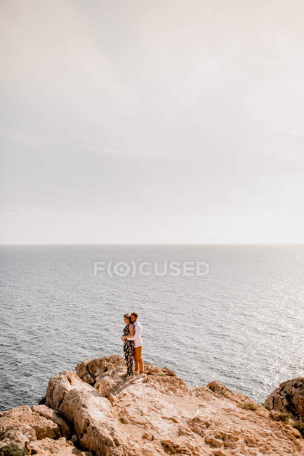Couple embracing on rock — Stock Photo