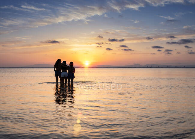 Women embracing on sunset at sea — Stock Photo