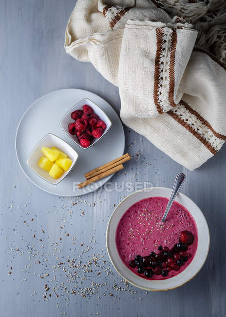 Bol lisse avec des petits fruits frais et du sésame servi sur table — Photo de stock