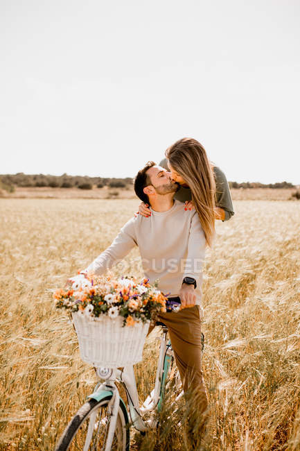 Playful lovers riding bicycle on wheat field — Stock Photo