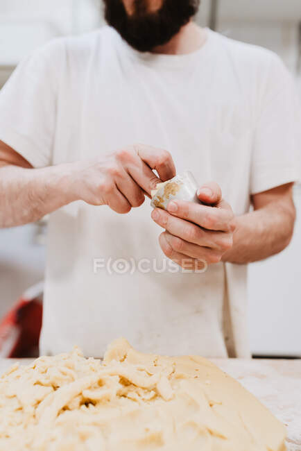 Da pasticcere anonimo mettendo pasta morbida fresca in piccola tazza sopra il tavolo in cucina panetteria — Foto stock