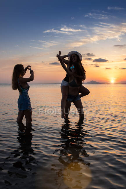 Joyful fellows posing and taking photos in water — Stock Photo