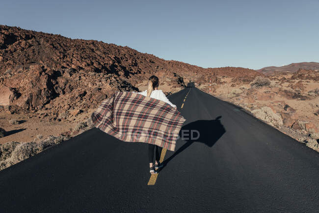 Mulher com xadrez andando na estrada vazia — Fotografia de Stock