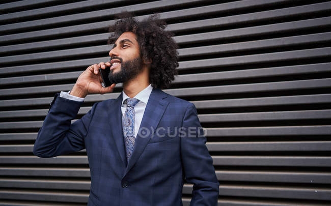 Hombre afroamericano hablando por teléfono cerca de la pared - foto de stock