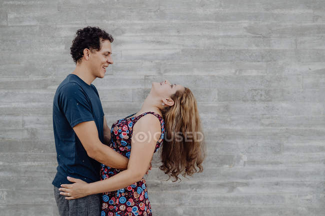 Man and woman looking at each other and embracing at nearby street wall — Stock Photo