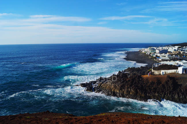 Paisagem incrível de casas brancas colocadas na costa remota de mar azul calmo sob céu infinito em Lanzarote, Ilhas Canárias, Espanha — Fotografia de Stock