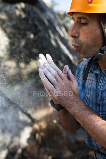 Un escalador sopla algo de polvo de tiza de sus manos - foto de stock